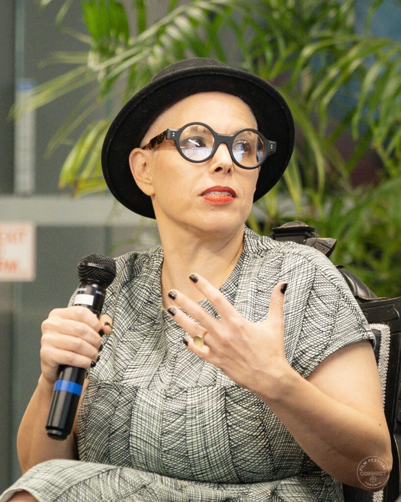 A panel participant in a black hat gestures while holding a microphone. AI & Film Forum, Panel 1, September 14, 2026.