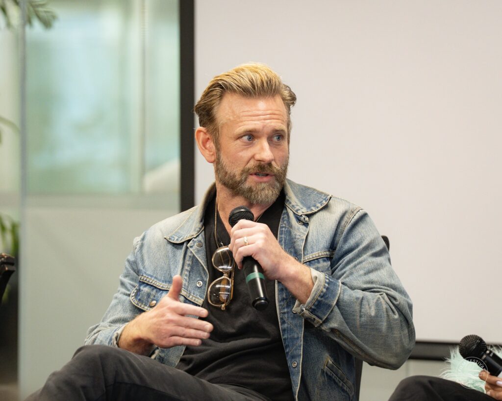 A panel participant in a denim jacket speaks into a microphone and gestures with his free hand. AI & Film Forum, Panel 1, September 14, 2026.