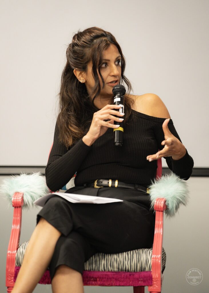 A panel participant in a black outfit speaks and gestures from a pink chair. AI & Film Forum, Panel 1, September 14, 2026.
