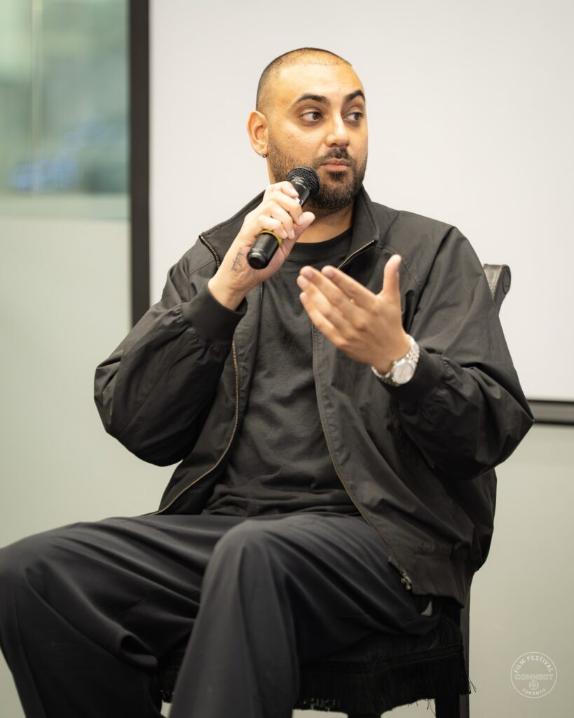 A panel participant in a black jacket speaks into a microphone with an open-hand gesture. AI & Film Forum, Panel 2, September 14, 2026.