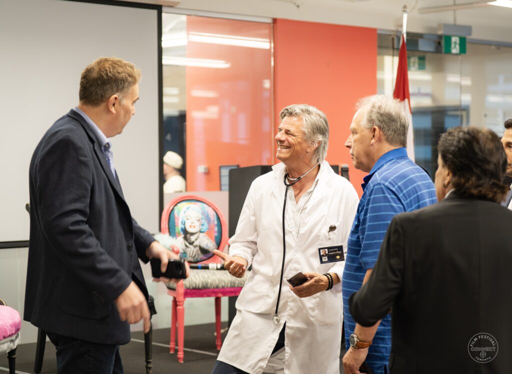 After the panel, a participant in a white coat talks with attendees beside the stage. AI & Film Forum, Panel 2, September 14, 2026.