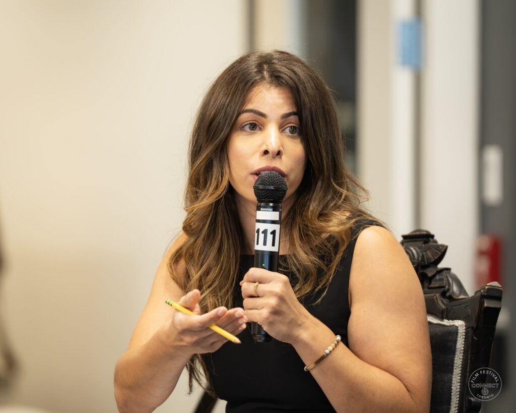 The moderator speaks into a microphone while gesturing with a pen. AI & Film Forum, Panel 3, September 14, 2026.