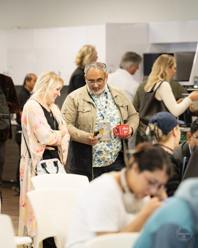 Two attendees look at an item together while others sit nearby at the AI & Film Forum.