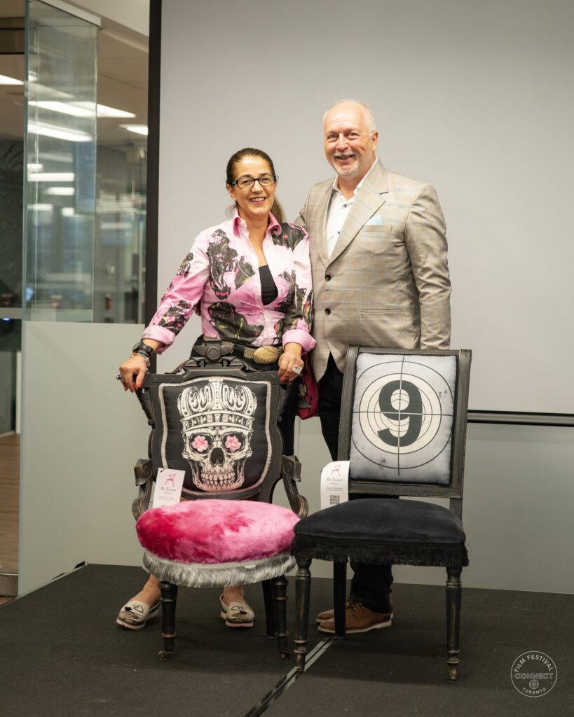 Two attendees pose behind the decorative chairs on the Forum stage.