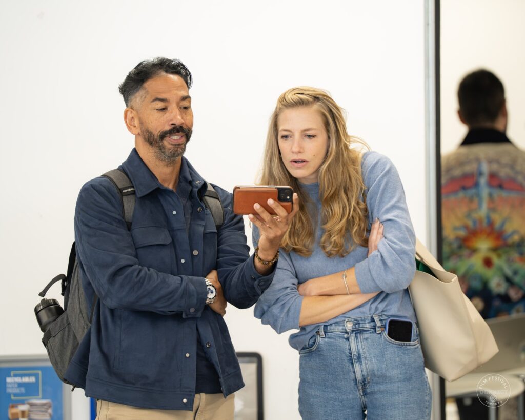 Two attendees look at a phone together during networking at the AI & Film Forum.