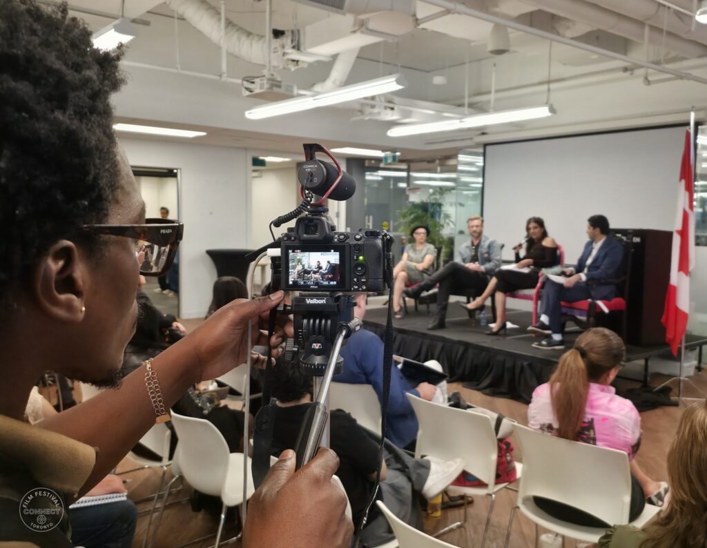A camera operator films the seated panel at the AI & Film Forum.