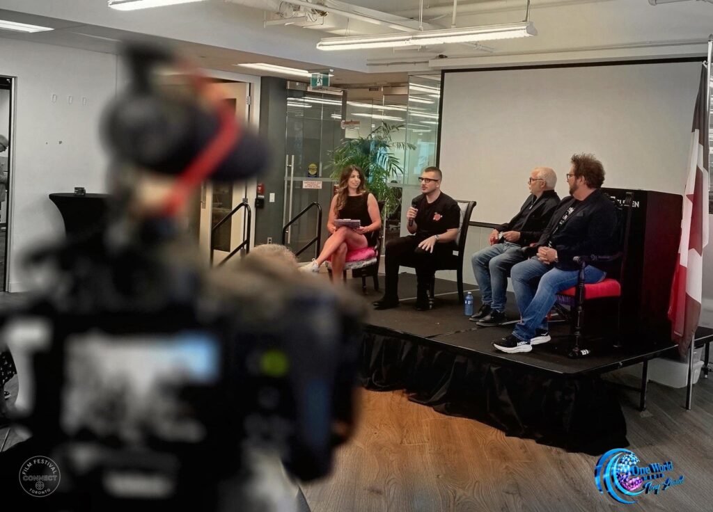 A camera in the foreground frames the panel on stage in the background.
